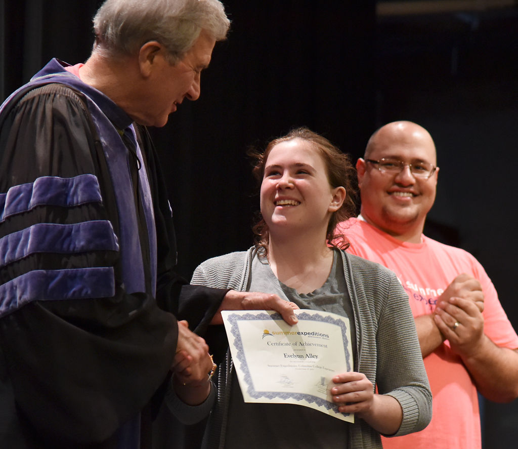 Terry Smith hands a certificate of achievement to eight-grader Evelynn Alley
